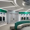 Binghamton University baseball stadium locker room with cubicles along the back walls full of uniforms and green and cream colored sofas in the center.