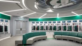 Binghamton University baseball stadium locker room with cubicles along the back walls full of uniforms and green and cream colored sofas in the center.