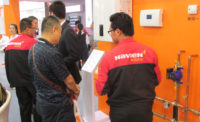 A Navien employee discusses the companyÃ?Â¢??s commercial condensing boiler with a booth visitor